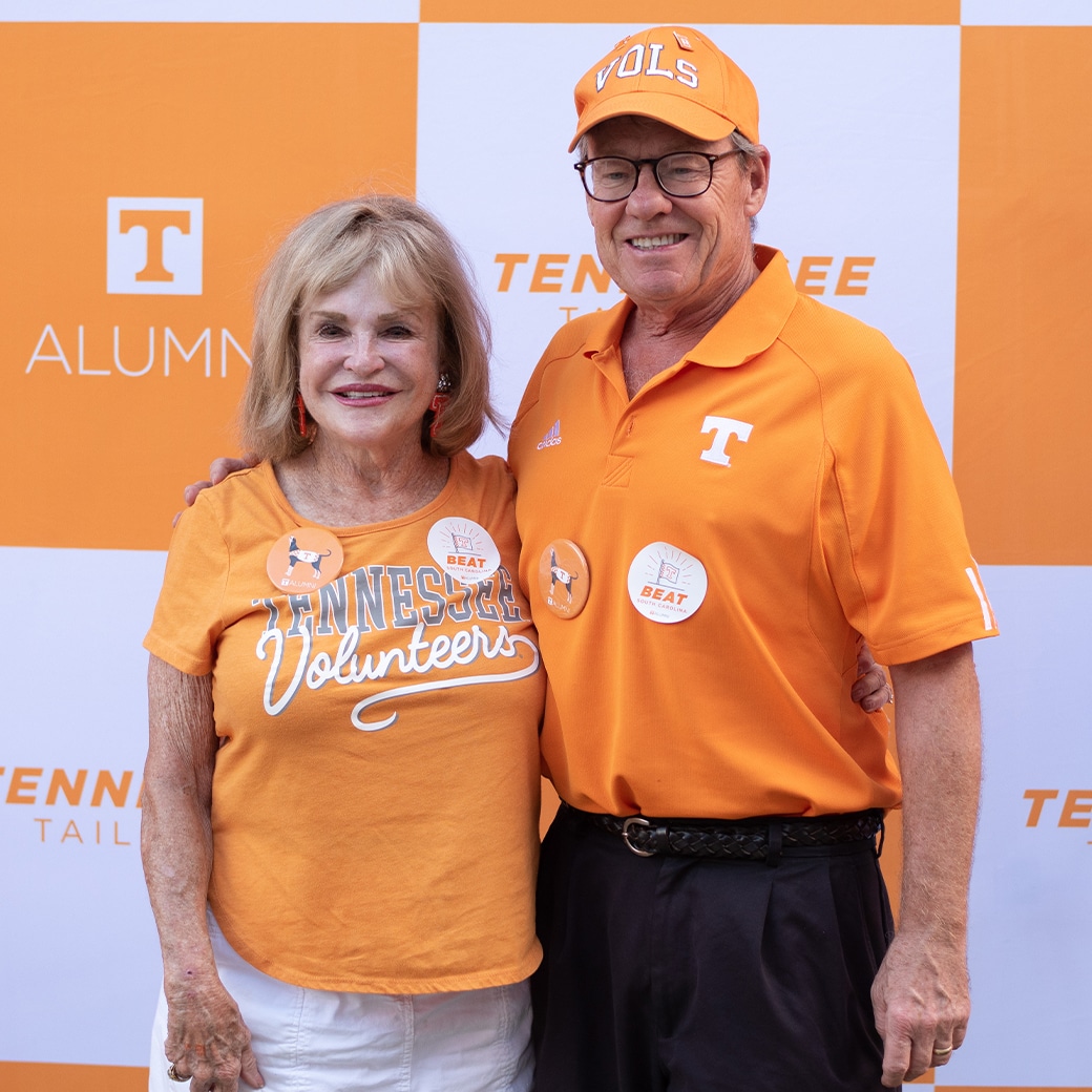 A man and woman in front of an orange-and-white checkered backdrop