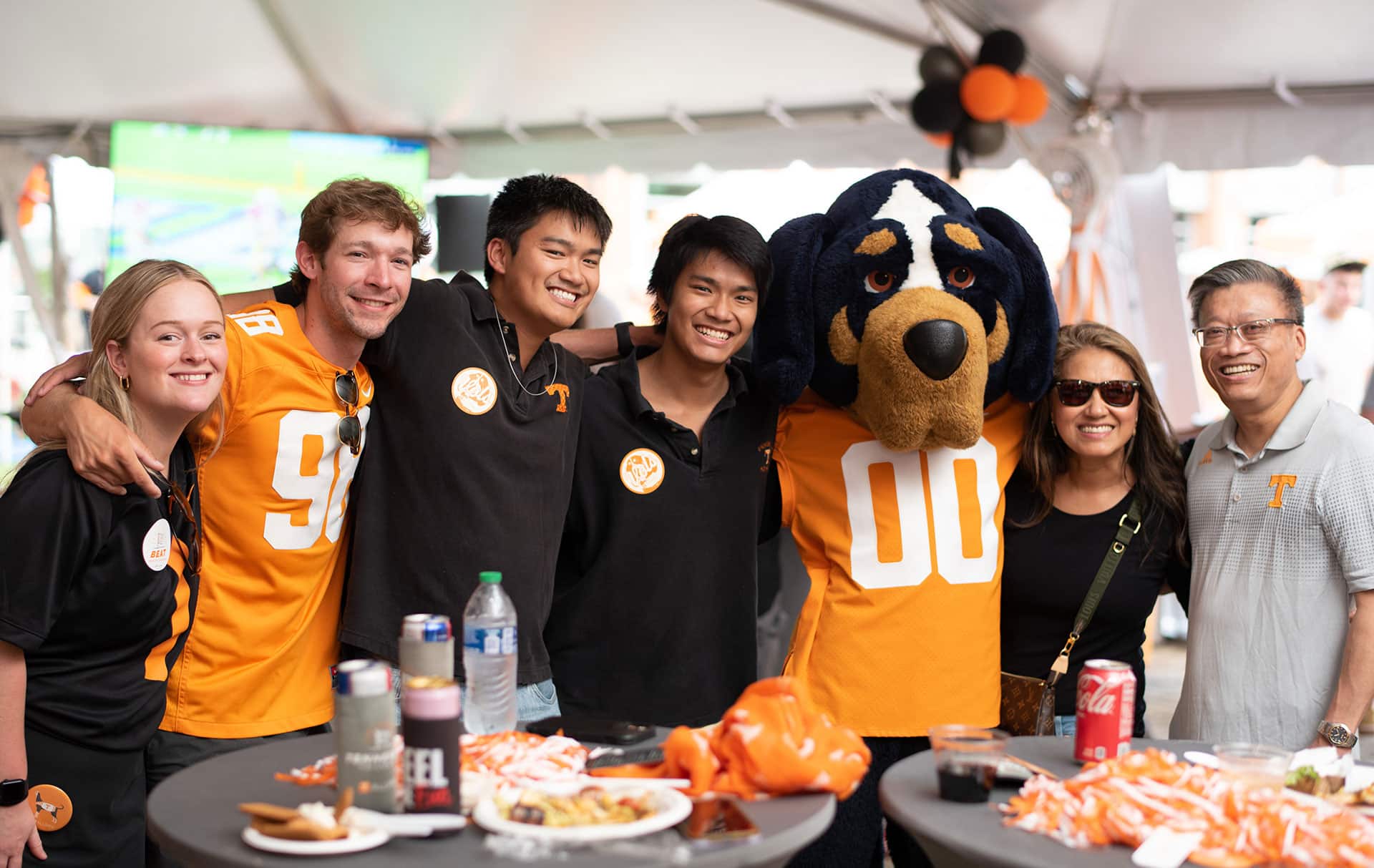 A group of alumni pose with Smokey during an alumni tailgate