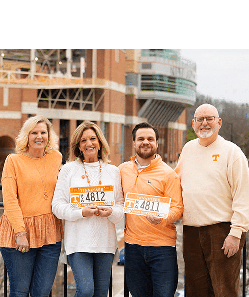 UT alums decked out in orange hold up their UT Alumni license plates
