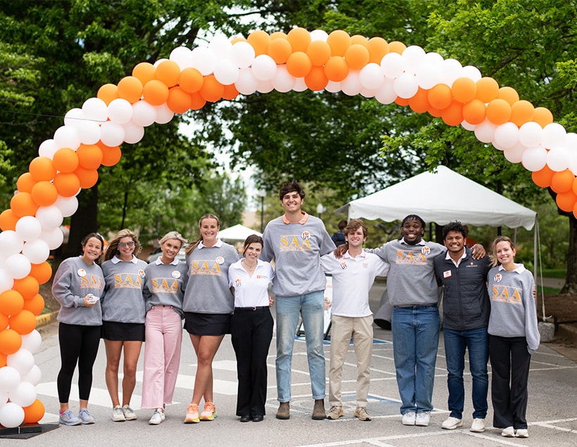 Members of the Student Alumni Associates stand under an orange-and-white balloon arch