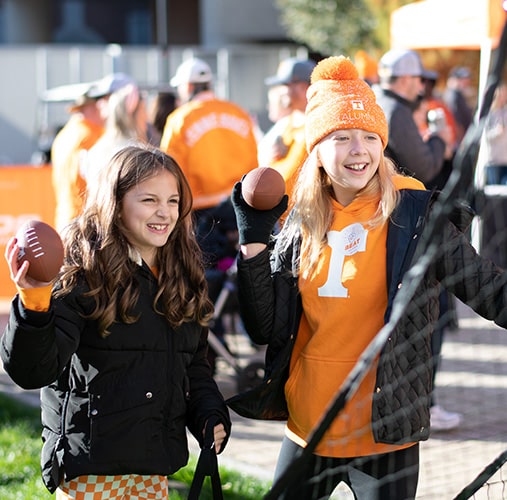 Two young girls preparing to throw footballs