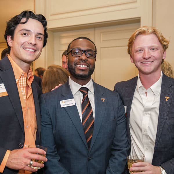 Three men pose for a photo during a reception