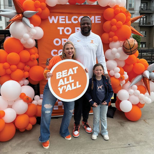 A woman, man, and young child pose at a tailgate photobooth