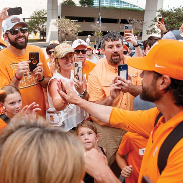 Coach Tony Vitello gives high-fives to Vol fans during a parade