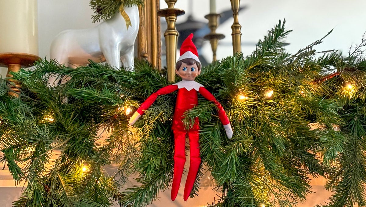 Elf on the Shelf surrounded by lighted garland