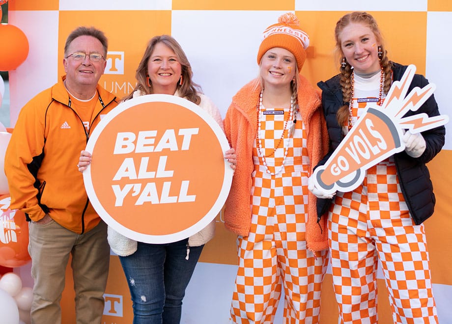 A family of 4 poses for a photo during a tailgate