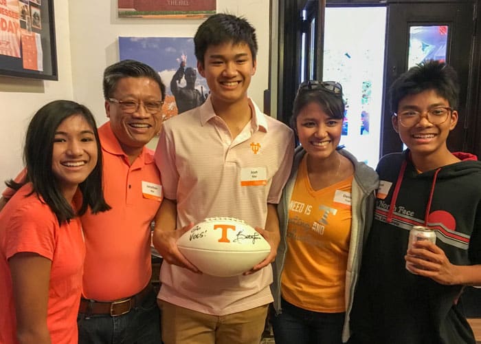 Jonathan Mai and Denise Tran with family during a UT tailgate. The boy in the middle of the group holds a signed UT football.