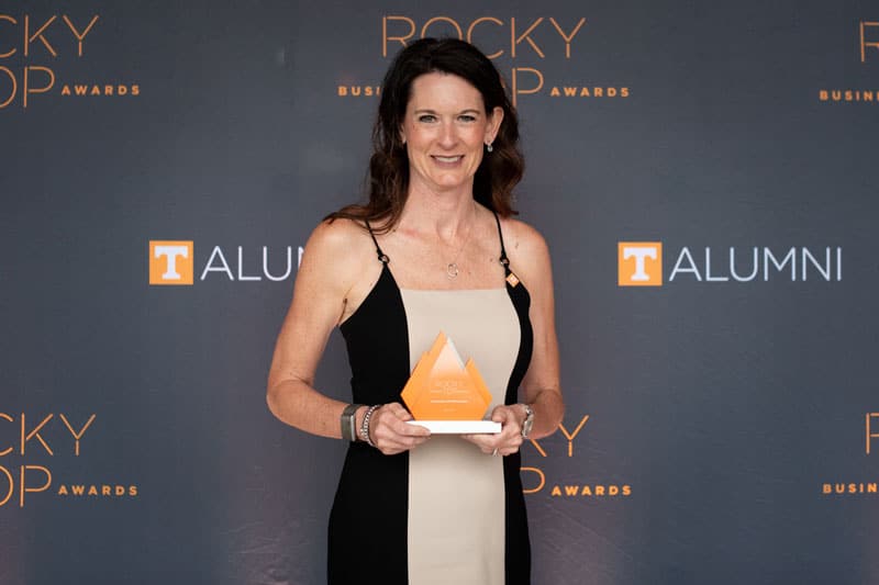 marden-kim-with-award-800x533 Kim Marden stands in front of a Rocky Top Business Awards step-and-repeat banner, holding an orange award.