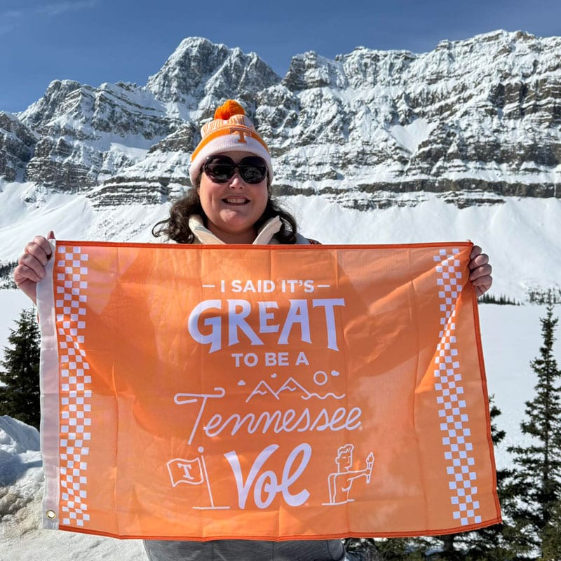 new-vol-day-800x800-3 A person in winter gear holds the It's Great to Be a Tennessee Vol flag. A snowcapped mountain is in the background.