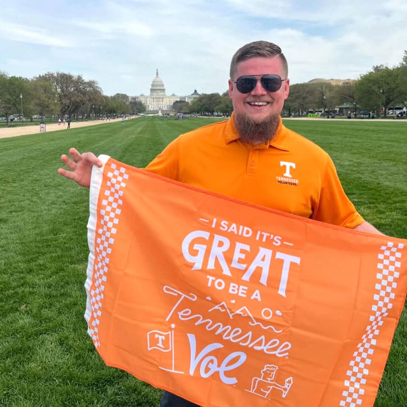 new-vol-day-800x800-5 A man holds up the It's Great to Be a Tennessee Vol flag in the National Mall. The U.S. Capitol is visible in the background.