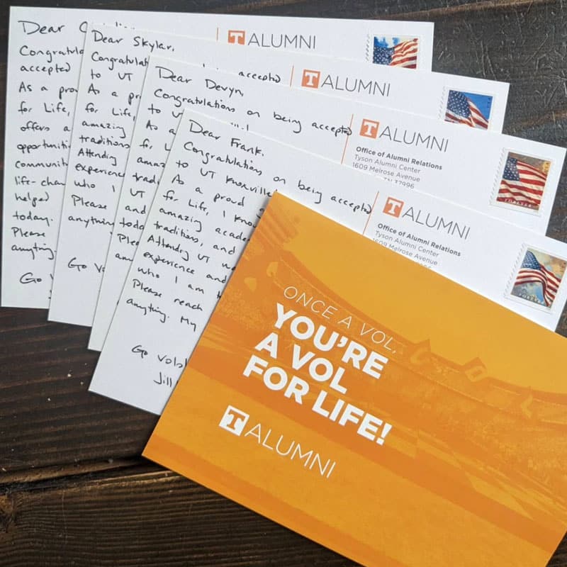 welcome-a-vol-postcards-800x800 A stack of 5 postcards splayed on a table. The top postcard is orange and says You're a Vol For Life!