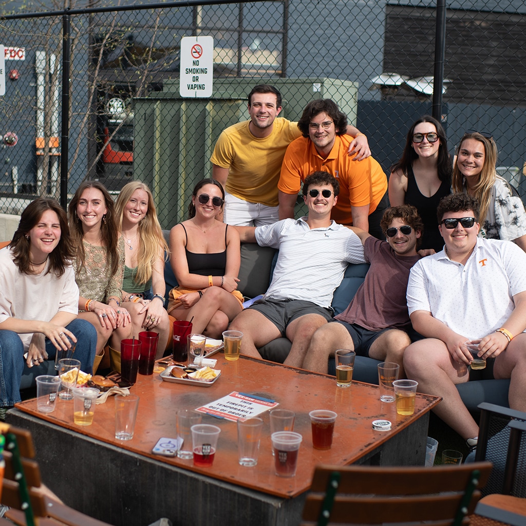 gallery-young-alumni A group of young alumni pose for a photo around a couch.