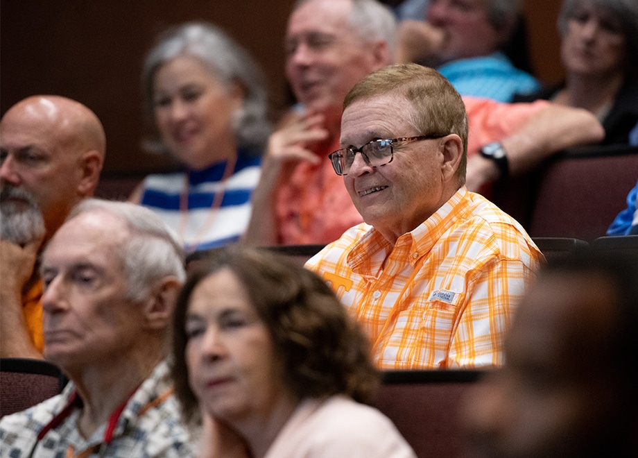 hero-alumni-summer-college A group of alumni sit together. The focus is on a man in glasses wearing an orange-and-white checked shirt.