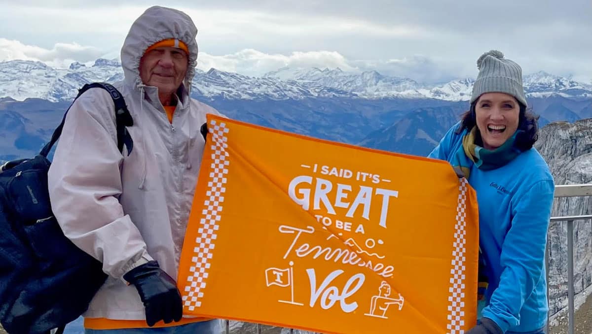 vantrease-jerry-and-jana-swiss-alps-1200x678 Jerry Vantrease and his daughter Jana Vantrease, wearing cold weather gear, hold an orange flag that says It's Great to Be a Tennessee Vol with the Swiss Alps in the background.