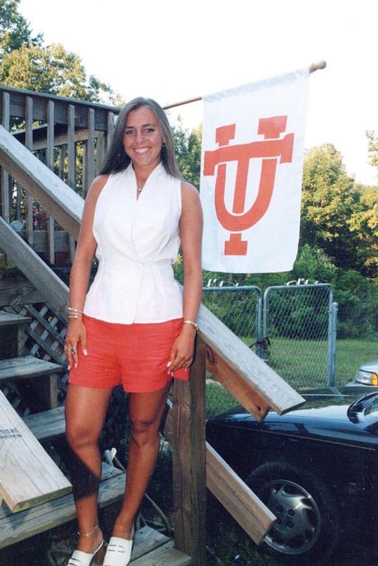 vieten-katrina-ut-flag-534x800 Katrina Vieten, in a white blouse and orange shorts, stands near a UT flag.