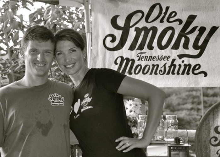 baker-joe-and-jessi-ole-smoky-moonshine-2509 Joe and Jessi Baker in front of an Ole Smoky Moonshine banner.