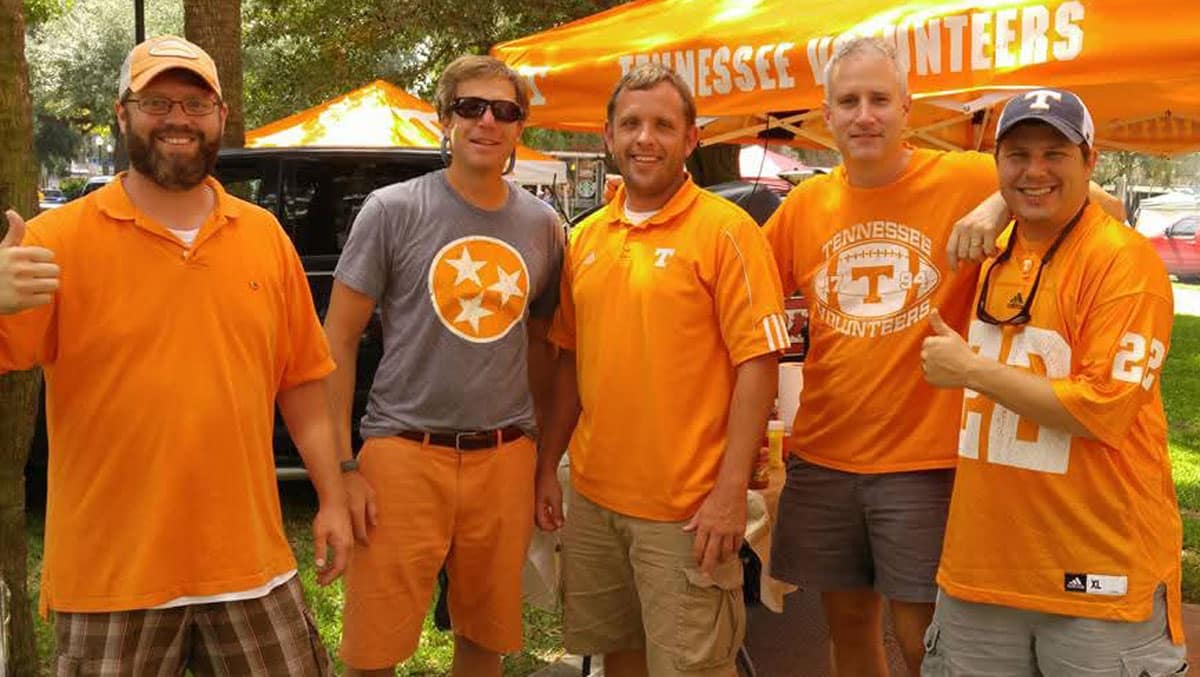 Five friends dressed in Tennessee orange during a football game tailgate.