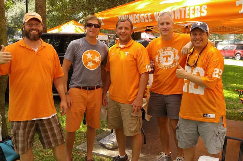 Five friends dressed in Tennessee orange during a football game tailgate.