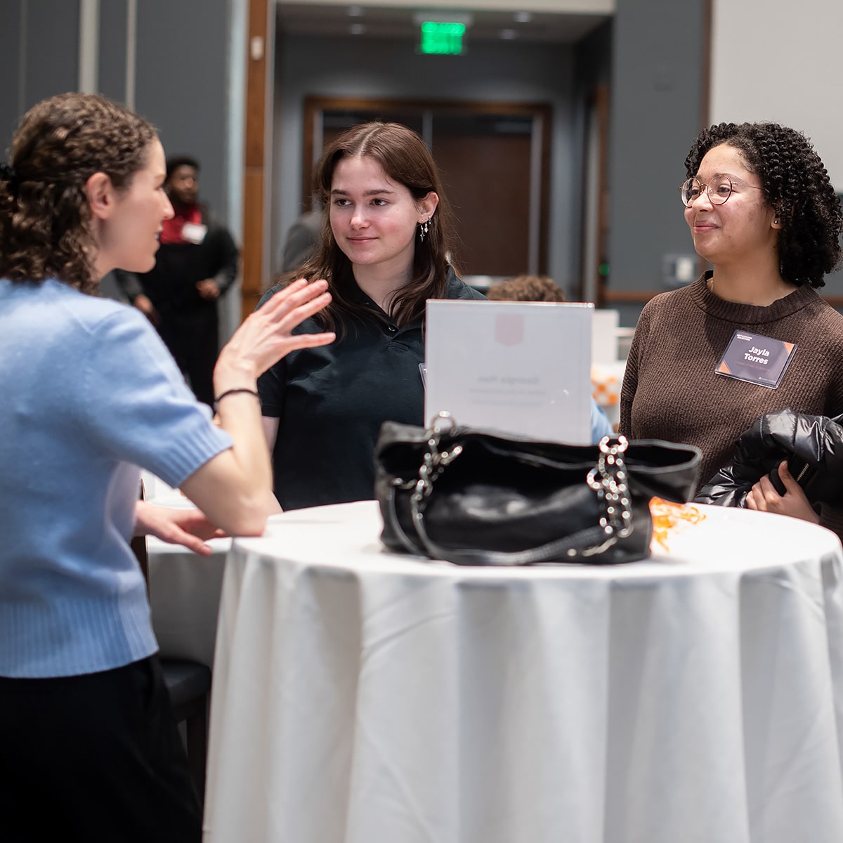 Poeple taking at a standing white table at event