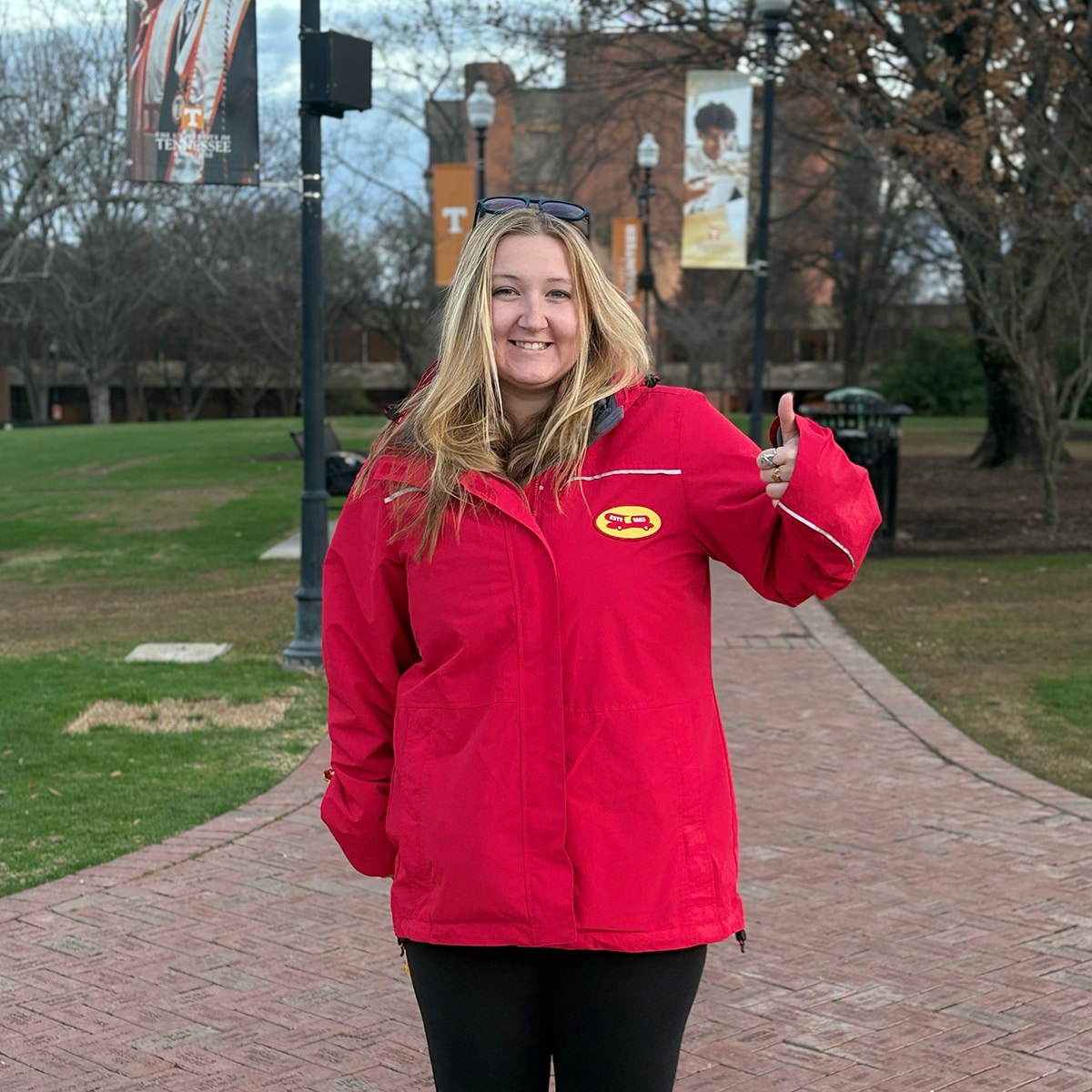 Person in red jacket smiling and giving the thumbs up 