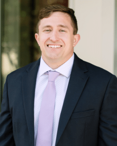 Person in suit with purple tie poses for a headshot