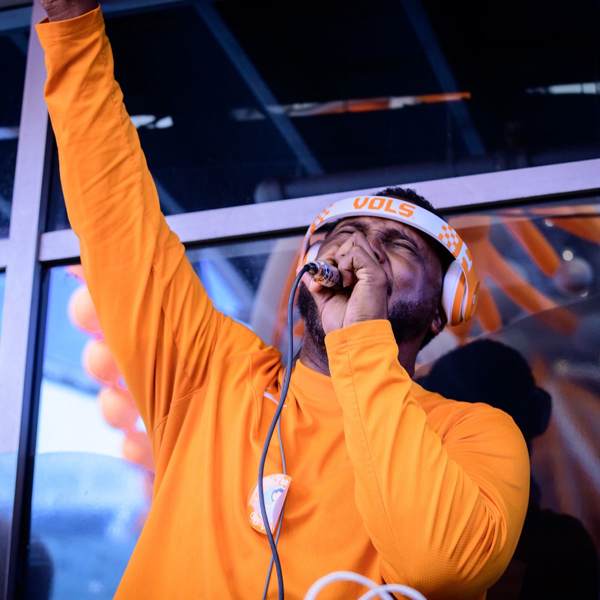 Person with a microphone yelling in orange shirt