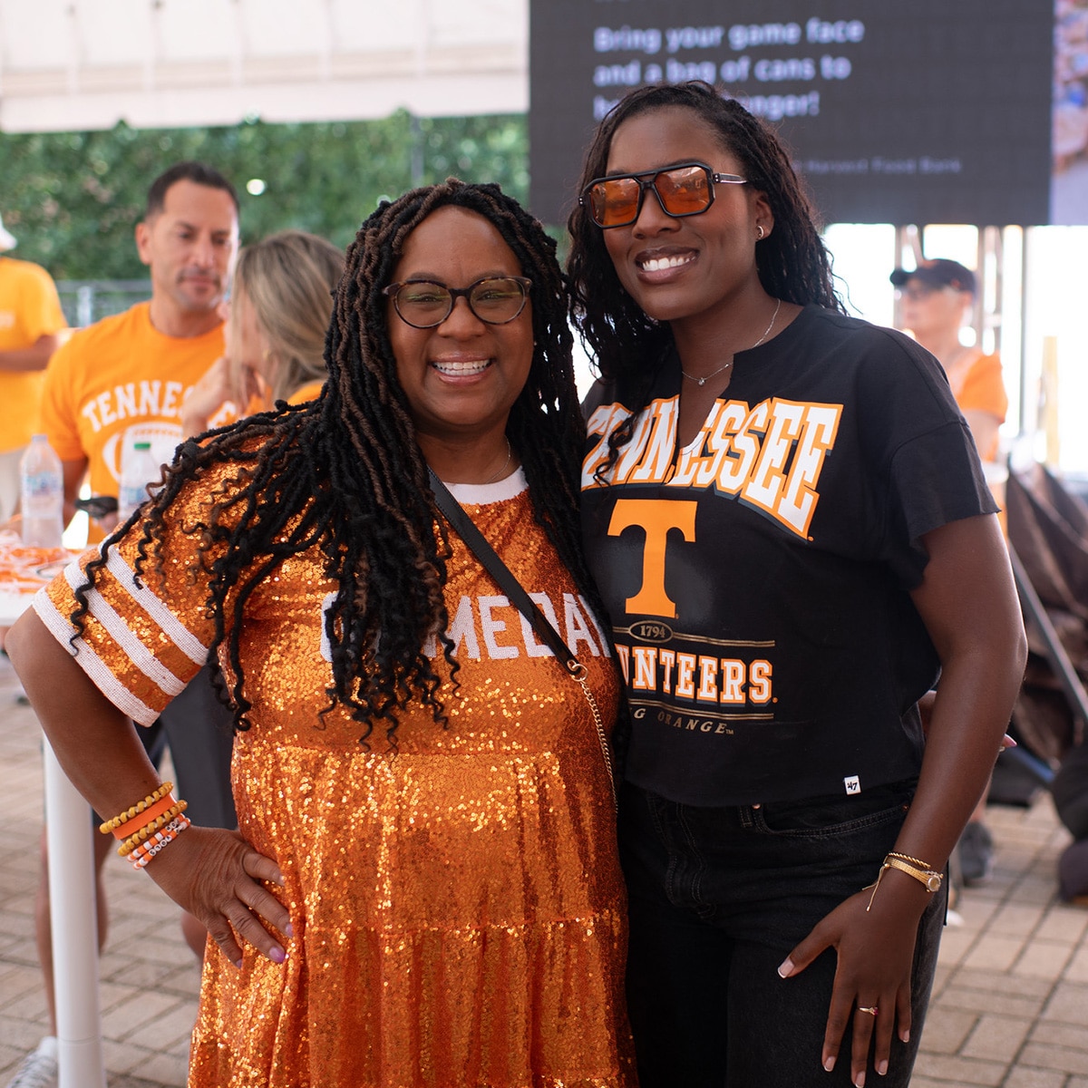 two people in vols shirts smiling at a tailgate