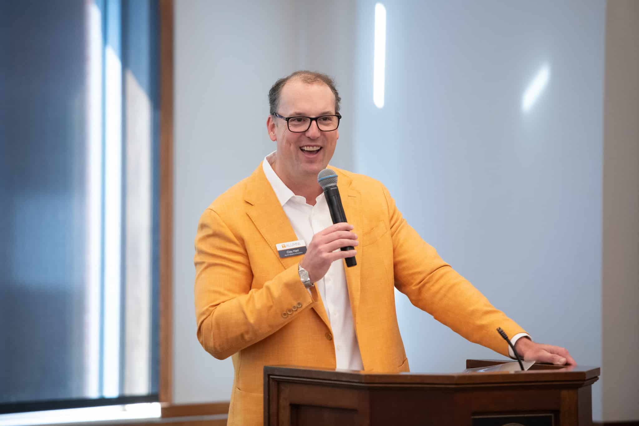 55295550233_9f86ebe6c8_k Clay hart in orange jacket smiling while talking into a microphone