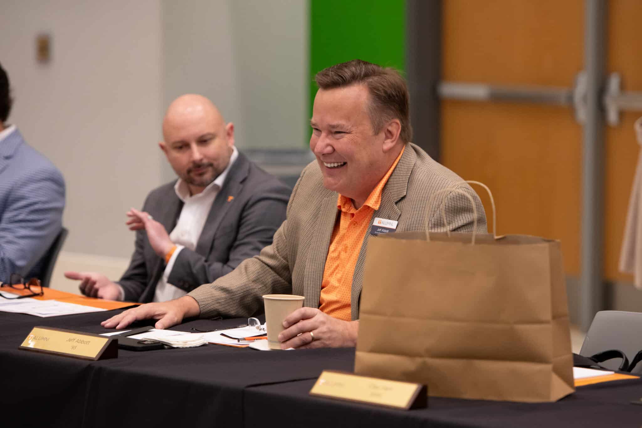 DSC_5531 Jeff Abbott smiling at a table with other attendees during an event.