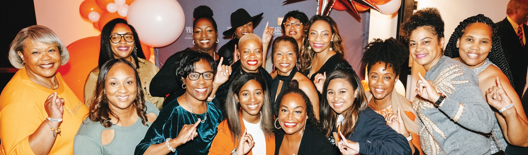 Attendees of a Black Alumni Council event pose for a photo in front of a UT backdrop